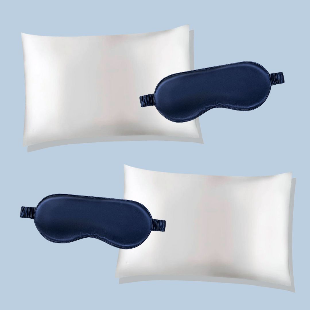 Two white silk pillowcases with navy blue sleep masks on a light blue background
